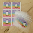 The image shows clear plastic storage bags and pink stickers with the phrase 'I Lost a Tooth!' printed on them, both featuring a tooth graphic.